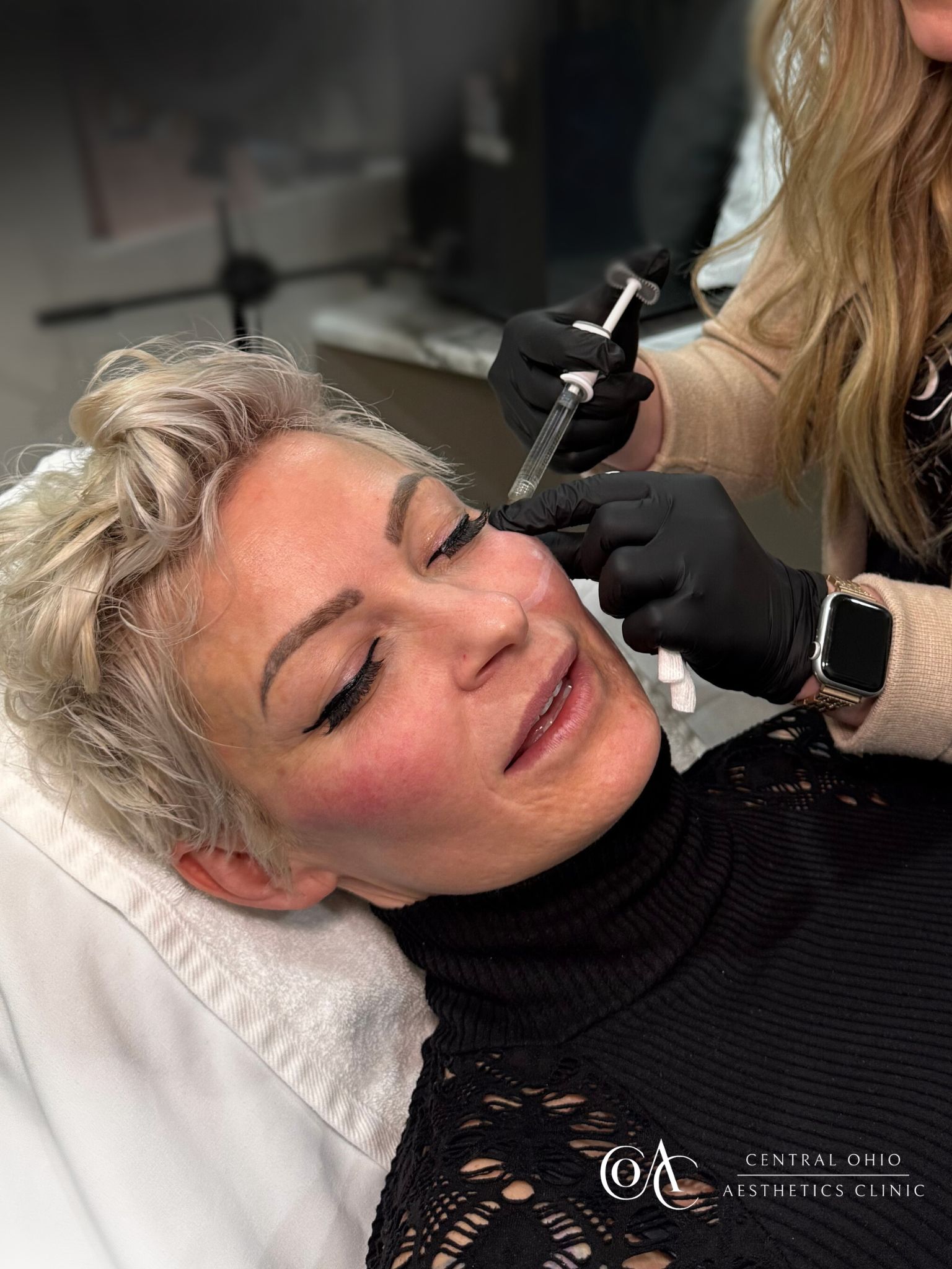 A woman receiving eyebrow shaping from a professional in a beauty salon setting. A woman receiving eyebrow shaping from a professional in a beauty salon setting.