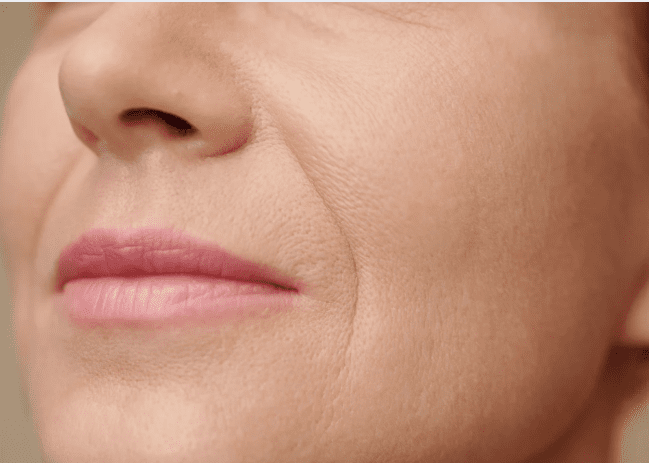 A close-up of a woman's face showing fine wrinkles, highlighting her age and experience.